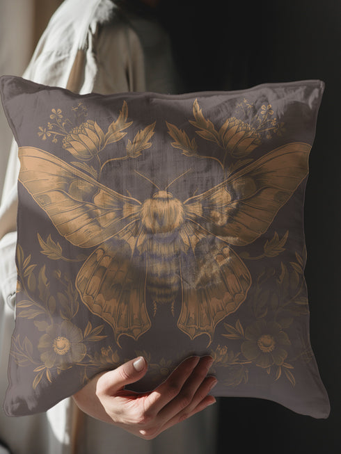 A decorative pillow cover featuring an intricately detailed Luna moth illustration in antique gold on a smoke gray background, surrounded by symmetrical botanical elements including flowers and delicate foliage.